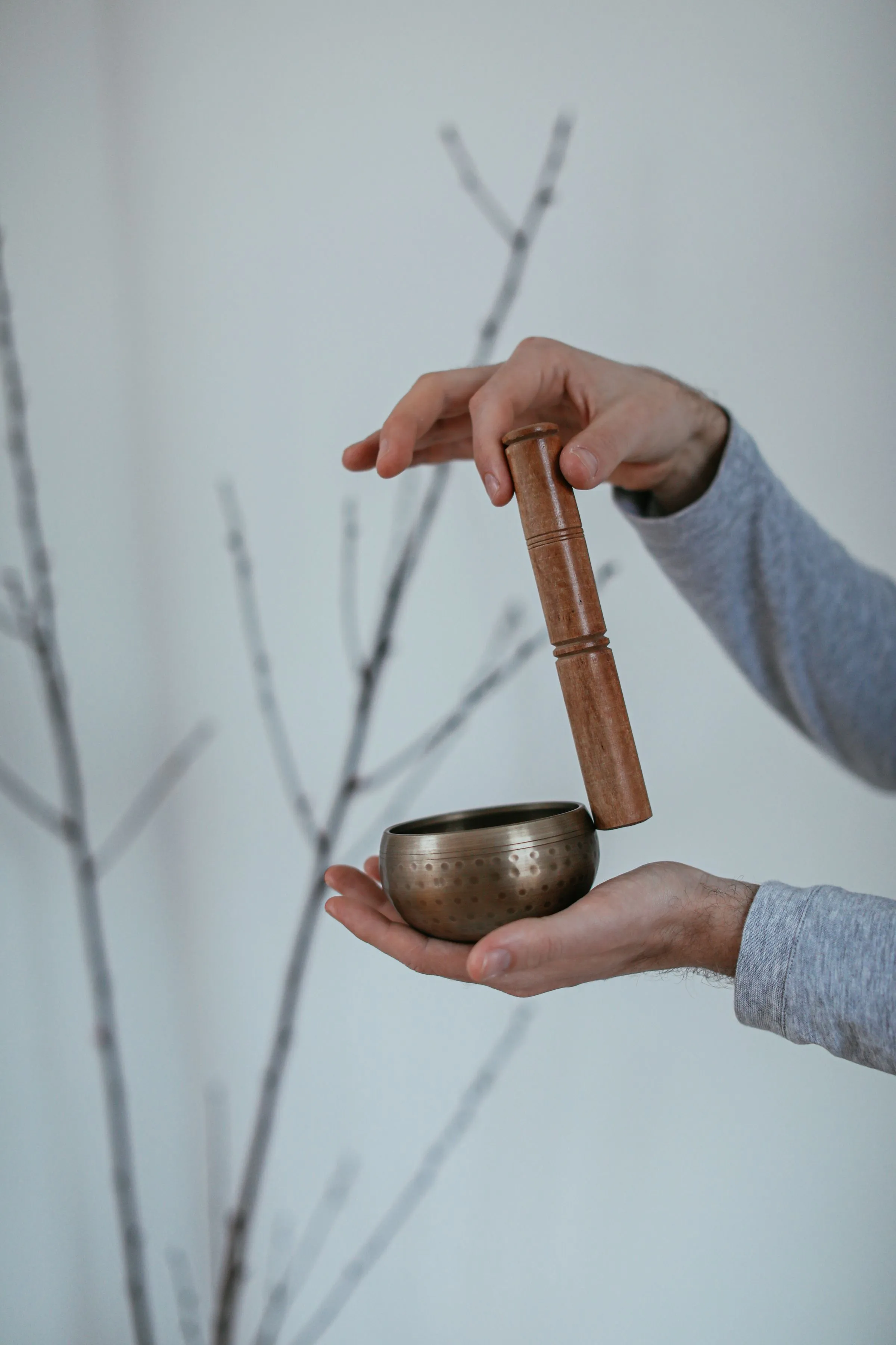 A singing bowl held in the hand with a wooden mallet